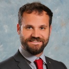 young man wearing suit and red tie, smiling. 