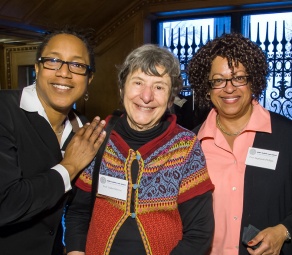three women, smiling at a social event. 