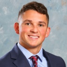 young man wearing a suit, tie, smiling. 