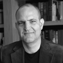 a black and white photo of a man in a library. 