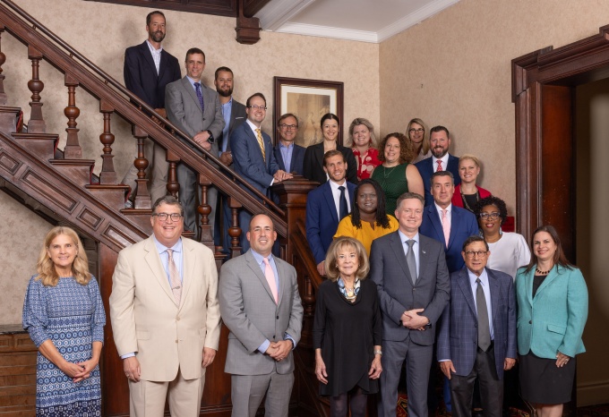 a photo of a large group of people, some standing on a stairwell. 