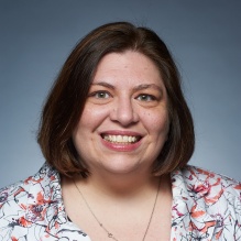 woman wearing flowery top, smiling. 