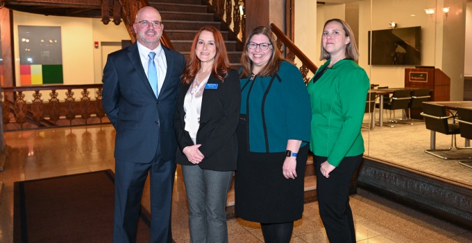 Group of people smiling, standing in a lobby. 