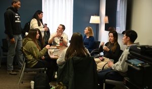 Group of young people, gathered around a table in a student lounge. 