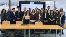 A group of people standing together in a meeting room, smiling. 