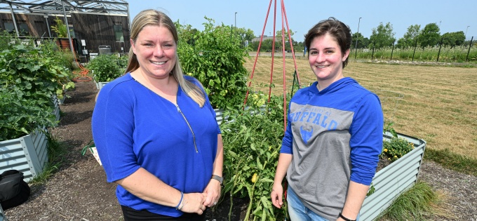Susan Adams and Emary Iacobucci standing outside in front of a vegetable garden. 
