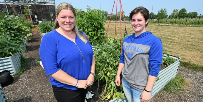 Susan Adams and Emary Iacobucci standing outside in front of a vegetable garden. 