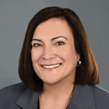 Woman wearing grey suit, smiling. 