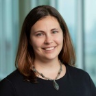Smiling woman standing next to office windows. 