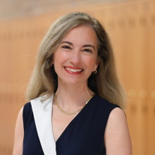 Bartholomew wearing black and white dress, standing in a hallway. 