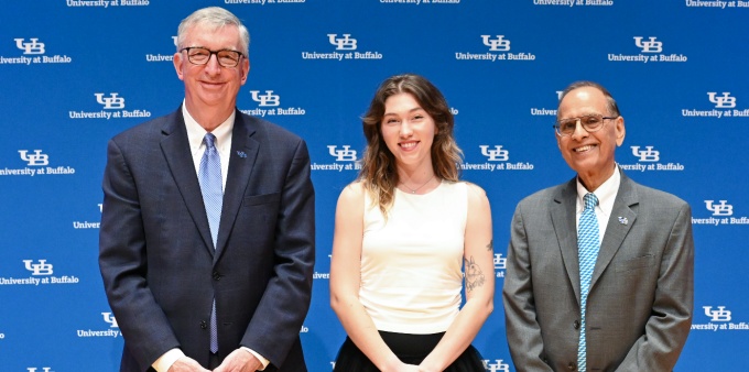 Three people, standing in front of a UB University at Buffalo screen, smiling. 