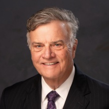 man smiling, wearing business suit and tie. 