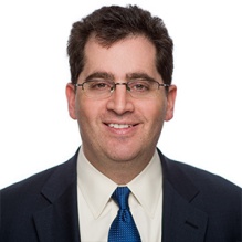 Smiling man wearing dark suit and tie. 