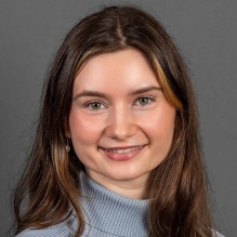 Young woman smiling, wearing knit sweater. 