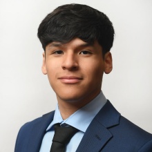 Young man wearing suit and tie, smiling. 