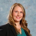 young woman wearing dark blu jacket, smiling. 