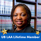 A person stands in front of a bookshelf filled with books. A blue banner at the bottom reads "UB LAA Lifetime Member" in white text, flanked by two gold stars. 