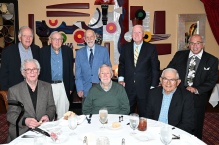 Group of men gathered at a table, celebrating their reunion. 