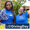 hree people standing outdoors wearing blue University at Buffalo shirts. One person holds a large blue foam finger with the word &lsquo;Buffalo&rsquo; printed on it. A UB Giving Day logo appears in the lower right corner, with trees visible in the background. 