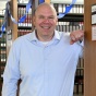 Brian Detweiler posing in the law library among rows of legal reference books decorated with blue streamers. 