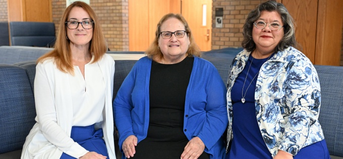 Three members of the law school community pose together in a campus common area. 