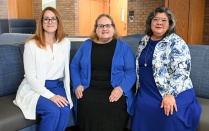 Three members of the law school community pose together in a campus common area. 
