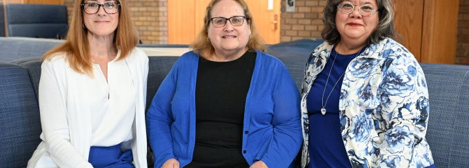 Three members of the law school community pose together in a campus common area. 
