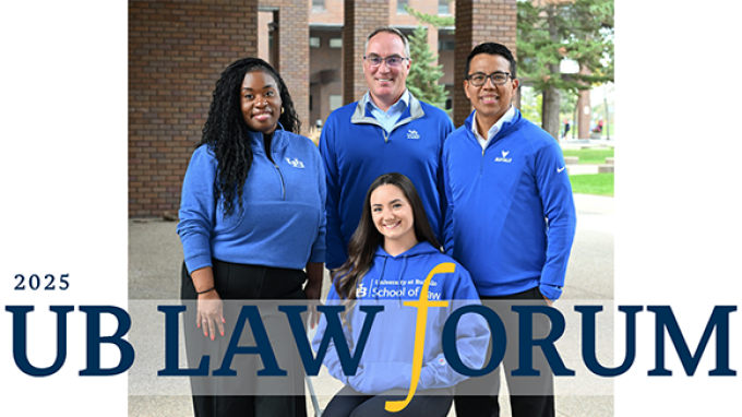 Four adults wearing blue UB Law apparel pose together outdoors on campus, with brick buildings and greenery in the background, alongside text reading &ldquo;2025 UB Law Forum.&rdquo;. 