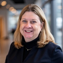 A photo of Christine (Smith) Howard wearing a black sweater and gold chain. 