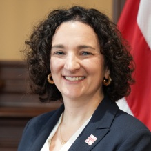 Portrait of Elizabeth Fox-Solomon with a flag behind her. 