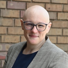 Angelyn McDuff wearing glasses, a blazer, and a dark top. 