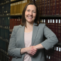 Professor Heather Abraham, director of the Civil Rights and Housing Clinic at UB School of Law, stands in the law library. 