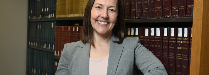 Professor Heather Abraham, director of the Civil Rights and Housing Clinic at UB School of Law, stands in the law library. 
