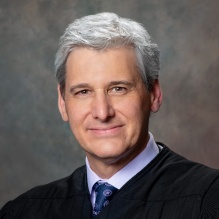 Smilingman wearing black judges robe.