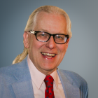 Prof. Schlegel wearing blue suit, red tie, smiling. 