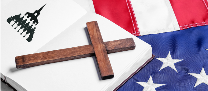 A wooden cross lies diagonally across the open pages of a book. On the left-hand page, there is a simple black graphic resembling a domed government building with rows of small figures beneath it. The book rests partly on top of an American flag, with the red-and-white stripes visible at the top of the image and blue fabric with white stars shown at the bottom right. 