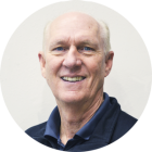 Person wearing a dark collared shirt and navy jacket against a plain light background.