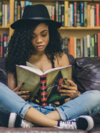 woman sitting on a leather couch reading a book. 