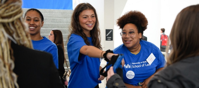 law students wearing blue t-shirts helping new law students as they arrive to attend orientation. 