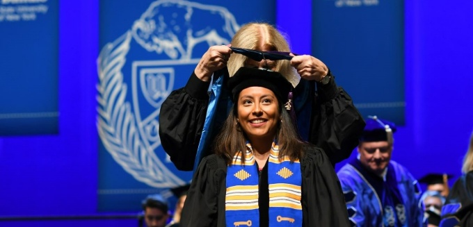 graduate receiving her hood during a commencement ceremony. 