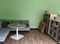 Zoom image: room with l-shaped sofa, wooden floors, coffee table and bookshelves