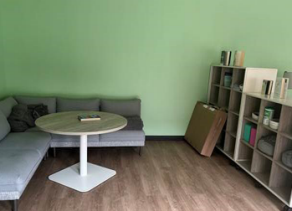 room with l-shaped sofa, wooden floors, coffee table and bookshelves. 