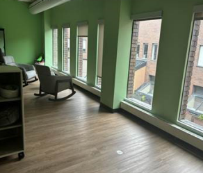 room with chairs, wooden floors and windows. 