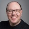 man wearing glasses, smiling.