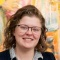 person wearing glasses standing against a colorful three dimensional painting.