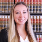 woman smiling, standing in front of a bookcase. 