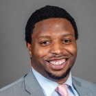 Eddie wearing grey suit, pink tie, smiling. 