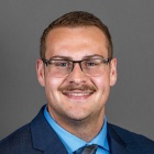 Skylar David Rehbein wearing blue jacket, tie. 