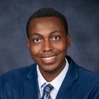 Andre Lloyd Jr. wearing blue jacket, tie, smiling. 