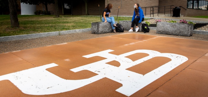 students sitting outside north campus, practicing social distancing. 